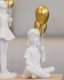 Escultura em Resina Branca Menina Sentada com Balão Dourado 10cm x 7,5cm x 22cm